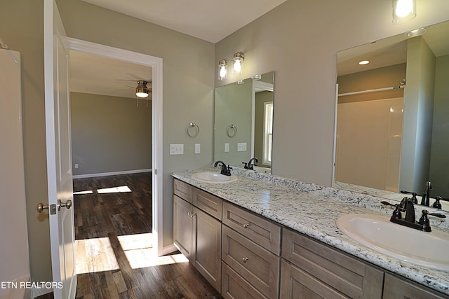 bathroom with dual bowl vanity, hardwood / wood-style floors, and ceiling fan