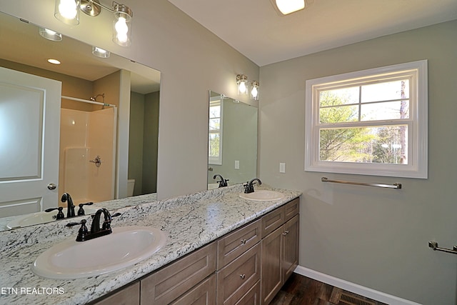 bathroom with dual sinks, toilet, large vanity, and hardwood / wood-style flooring