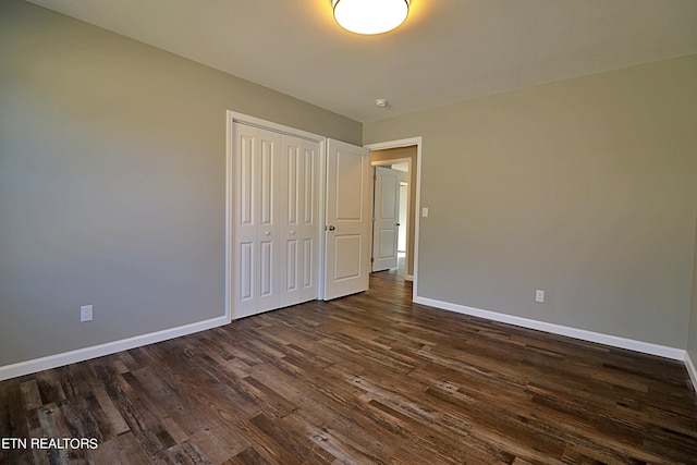 unfurnished bedroom featuring dark hardwood / wood-style flooring and a closet