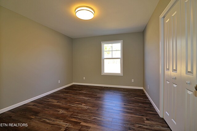 unfurnished bedroom with dark hardwood / wood-style floors and a closet