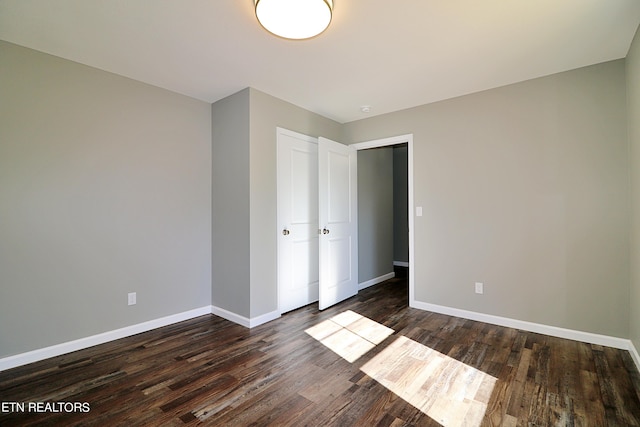 unfurnished bedroom with dark hardwood / wood-style floors and a closet