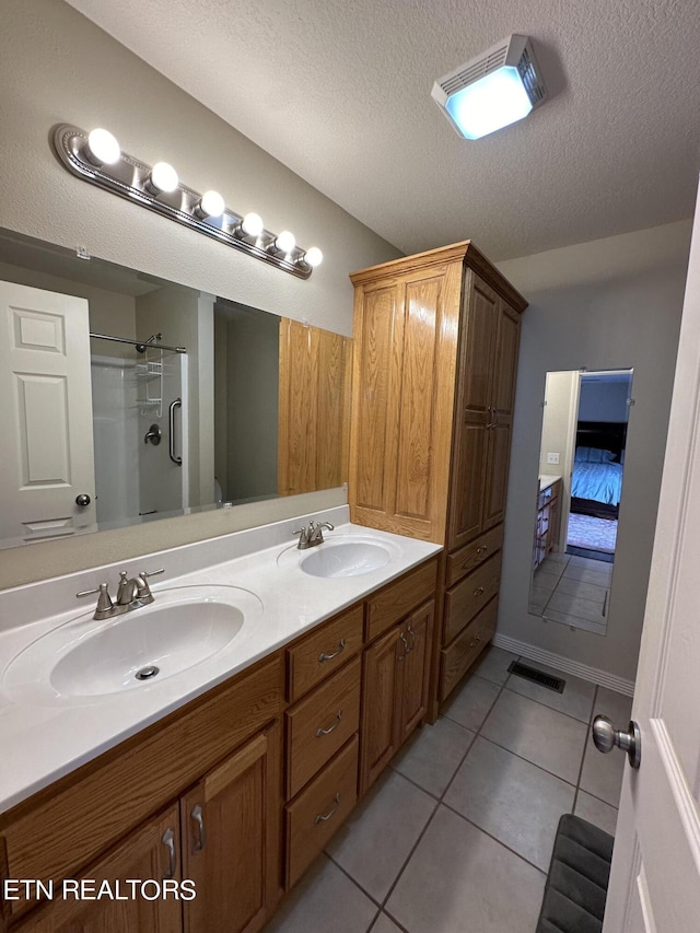 bathroom with large vanity, dual sinks, tile floors, and a textured ceiling