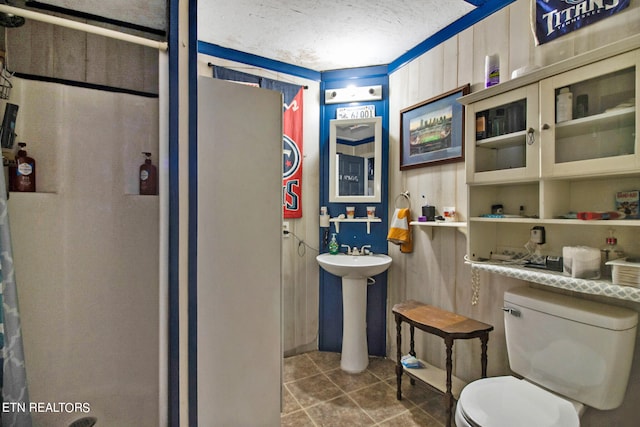 bathroom with toilet, tile flooring, a textured ceiling, and sink