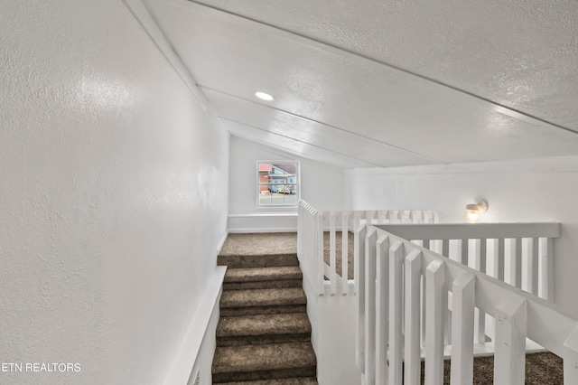 staircase featuring carpet, lofted ceiling, and a textured ceiling