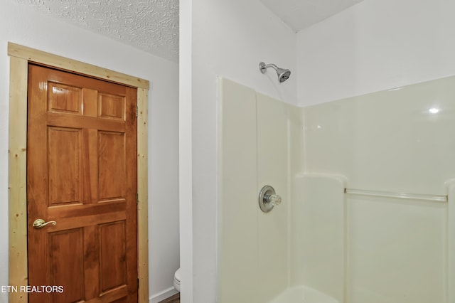 bathroom featuring toilet, walk in shower, and a textured ceiling