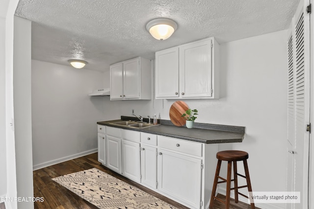 kitchen with sink, dark wood-type flooring, a textured ceiling, and white cabinets