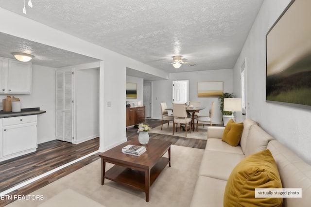 living room with a textured ceiling, ceiling fan, and hardwood / wood-style flooring