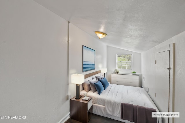 bedroom featuring lofted ceiling and a textured ceiling