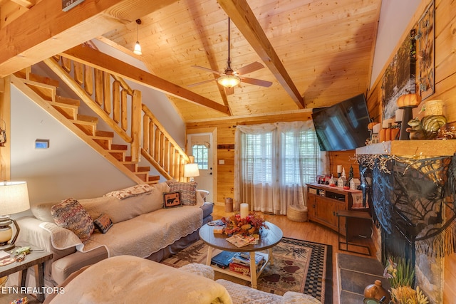 living room featuring wood walls, wood ceiling, vaulted ceiling with beams, and ceiling fan