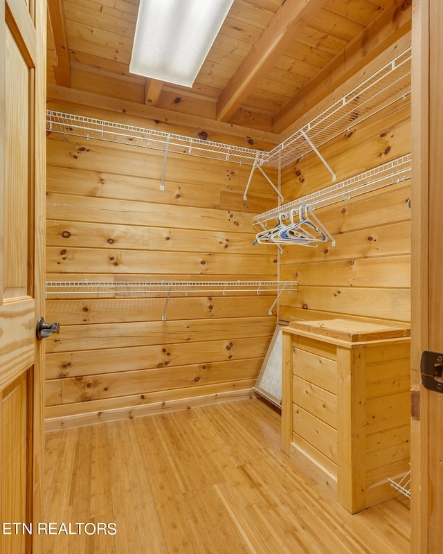 spacious closet with light hardwood / wood-style flooring and beamed ceiling