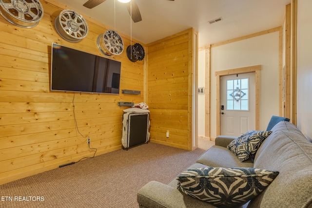 carpeted living room with wooden walls and ceiling fan