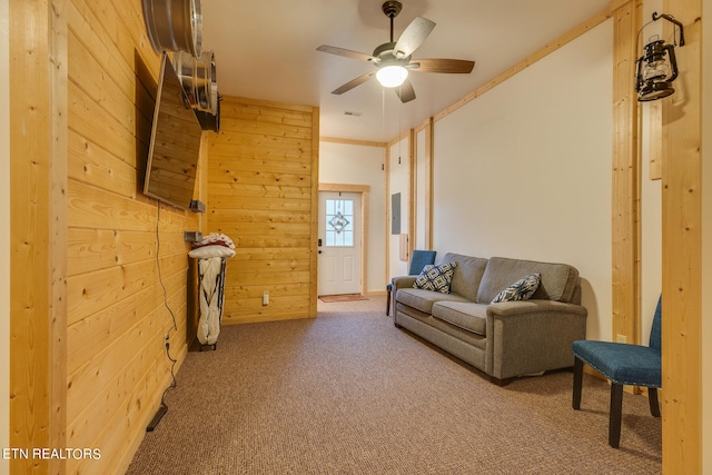 living room featuring ornamental molding, wooden walls, ceiling fan, and light colored carpet