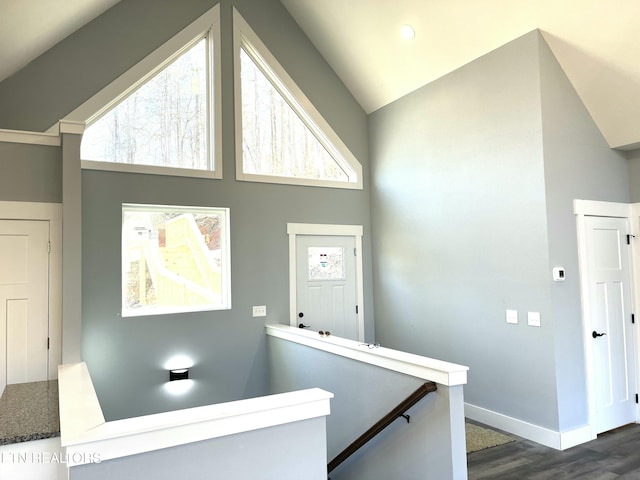 interior space with high vaulted ceiling, baseboards, dark wood finished floors, and an upstairs landing