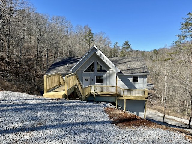 view of front of home featuring roof with shingles, board and batten siding, and a wooden deck