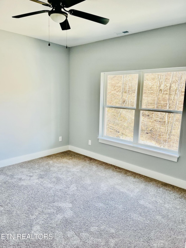 carpeted spare room featuring ceiling fan and baseboards