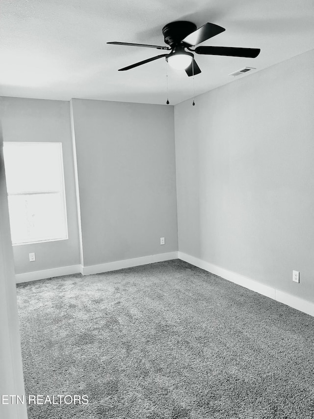 carpeted empty room with baseboards, visible vents, and a ceiling fan