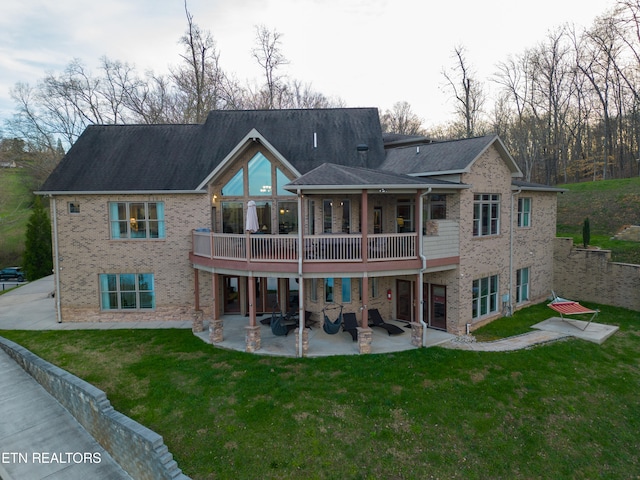 rear view of property with a balcony, a lawn, and a patio