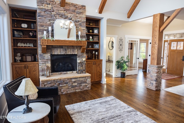 living room with an inviting chandelier, a fireplace, lofted ceiling with beams, built in shelves, and dark hardwood / wood-style floors