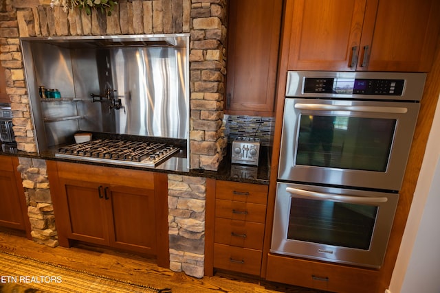 kitchen featuring light hardwood / wood-style floors, stainless steel appliances, and dark stone counters