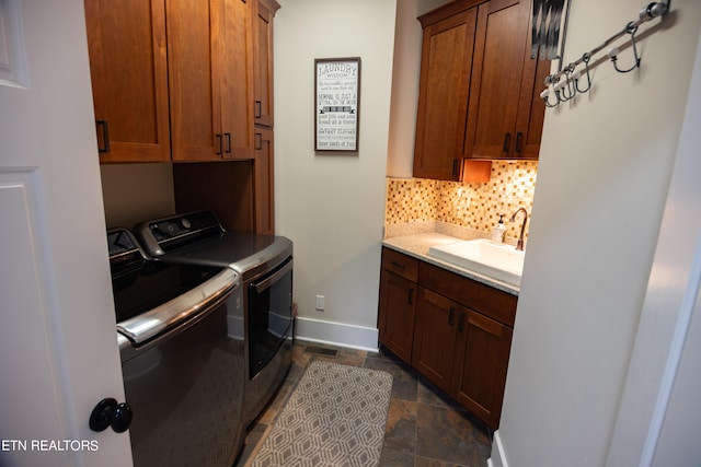 laundry room with dark tile floors, cabinets, washing machine and clothes dryer, and sink