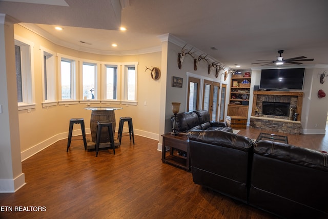 living room with crown molding, a fireplace, ceiling fan, and dark wood-type flooring