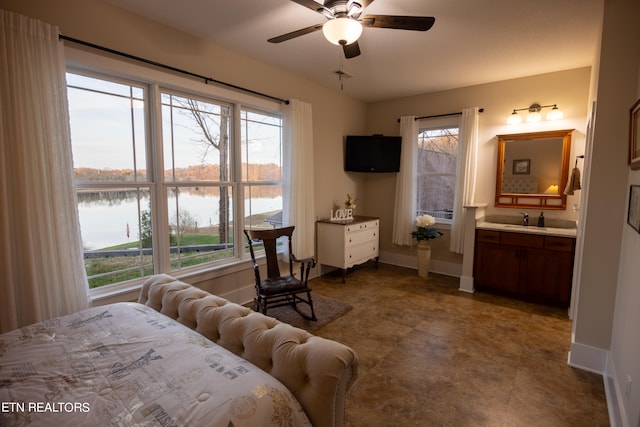 tiled bedroom featuring connected bathroom, ceiling fan, sink, and a water view