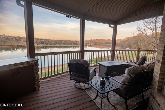 deck at dusk featuring a water view