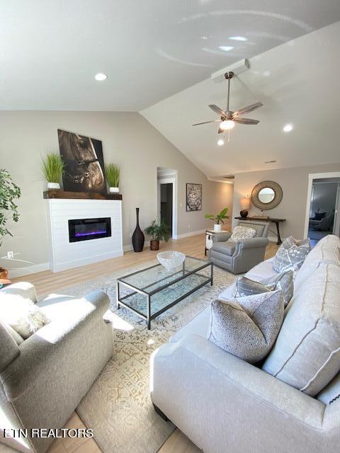 living room featuring hardwood / wood-style floors, ceiling fan, and vaulted ceiling