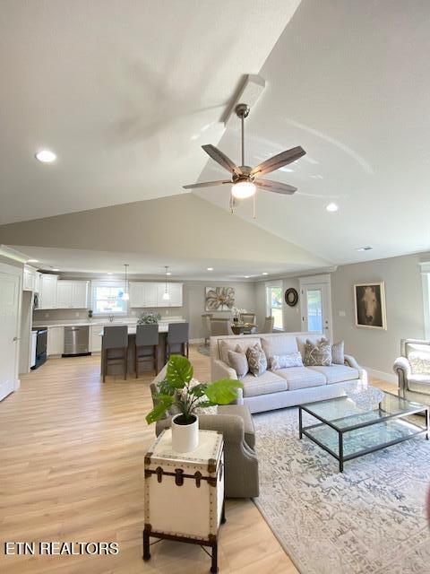 living room featuring ceiling fan, vaulted ceiling, and light hardwood / wood-style flooring