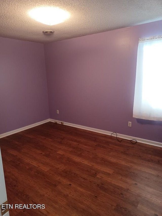 empty room featuring a textured ceiling and dark hardwood / wood-style floors