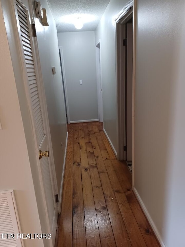 corridor featuring light hardwood / wood-style floors and a textured ceiling