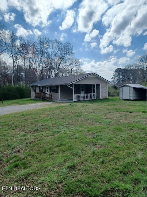 view of front facade featuring a front yard, a porch, and a storage shed