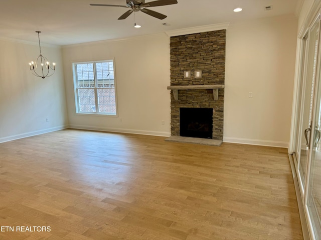 unfurnished living room featuring ornamental molding, a stone fireplace, ceiling fan with notable chandelier, and light wood-type flooring