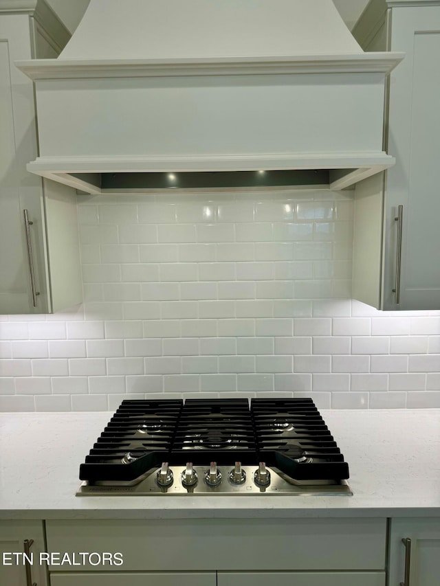 details with gray cabinetry, gas cooktop, light stone counters, and decorative backsplash