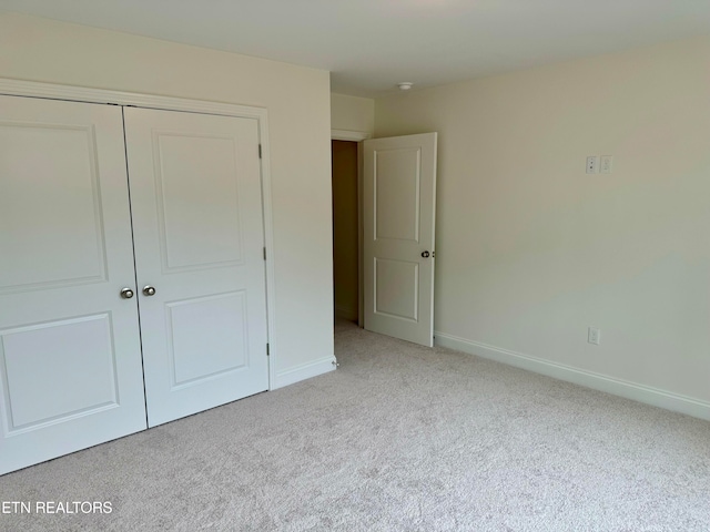 unfurnished bedroom with light carpet and a closet