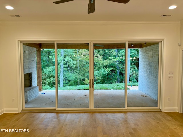 entryway featuring crown molding, ceiling fan, a brick fireplace, and hardwood / wood-style flooring