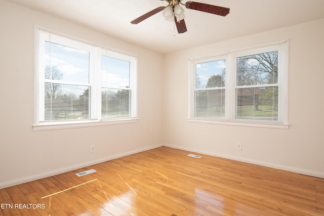 unfurnished room featuring ceiling fan, a wealth of natural light, and light wood-type flooring