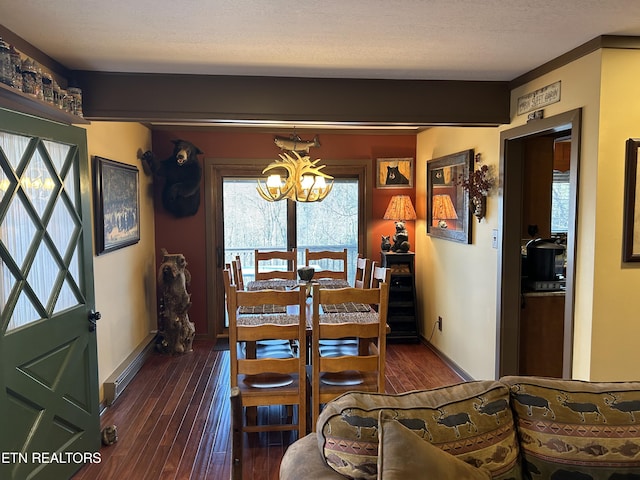 dining space with a textured ceiling, a chandelier, and dark wood-type flooring