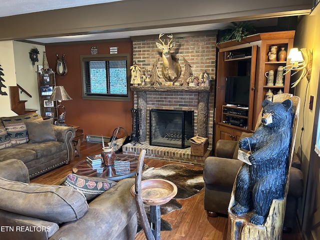 living room featuring brick wall, a fireplace, and dark hardwood / wood-style flooring