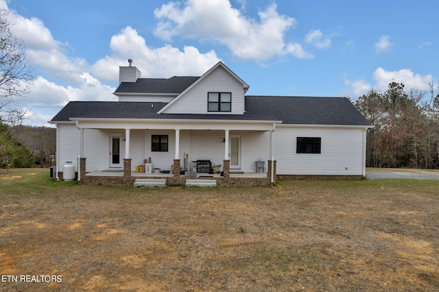 back of house with central AC unit, a porch, and a lawn