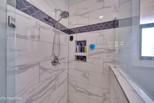 bathroom featuring tile walls and a tile shower