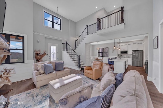 living room featuring a high ceiling, a chandelier, a wealth of natural light, and light wood-type flooring