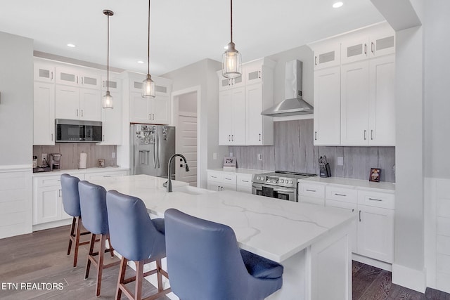 kitchen with tasteful backsplash, pendant lighting, stainless steel appliances, and wall chimney exhaust hood