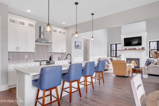 kitchen featuring decorative light fixtures, a breakfast bar, tasteful backsplash, wall chimney exhaust hood, and dark hardwood / wood-style floors