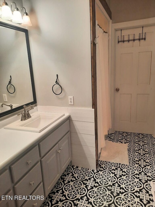 full bath featuring tile patterned flooring, a wainscoted wall, vanity, and tile walls