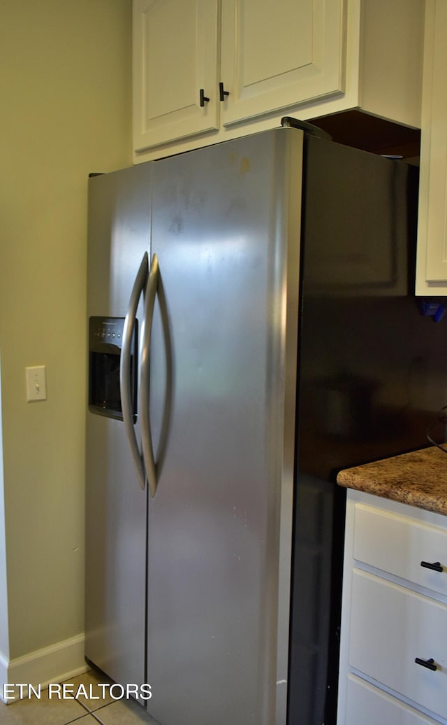 kitchen featuring light tile patterned floors, stainless steel fridge with ice dispenser, and white cabinetry