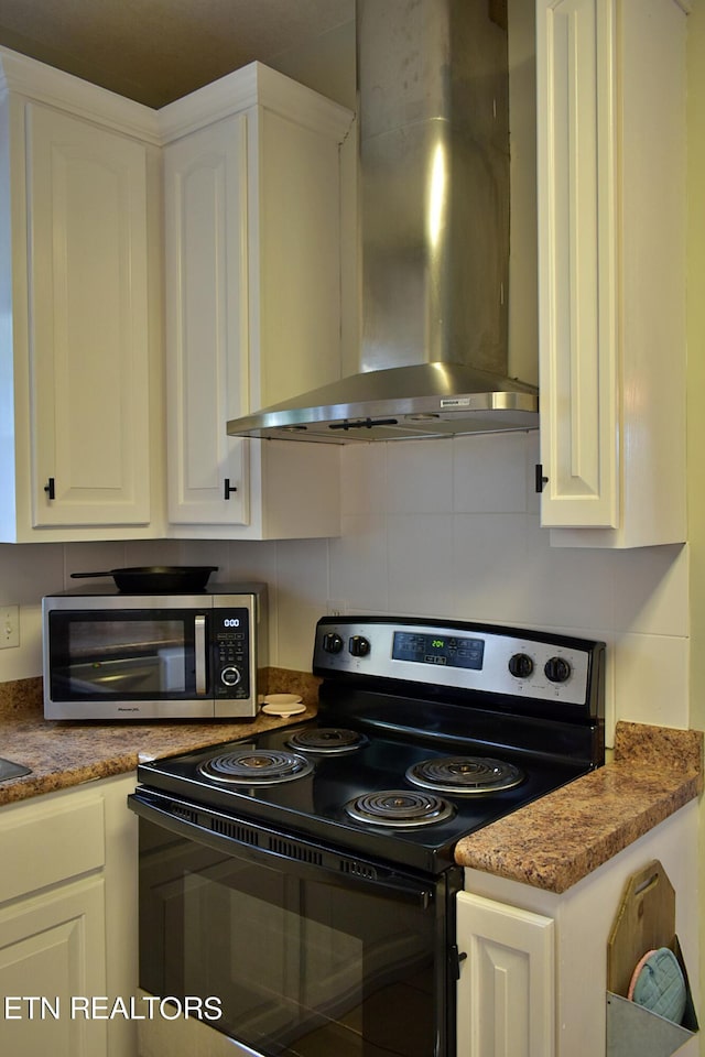 kitchen with wall chimney range hood, white cabinets, and range with electric cooktop