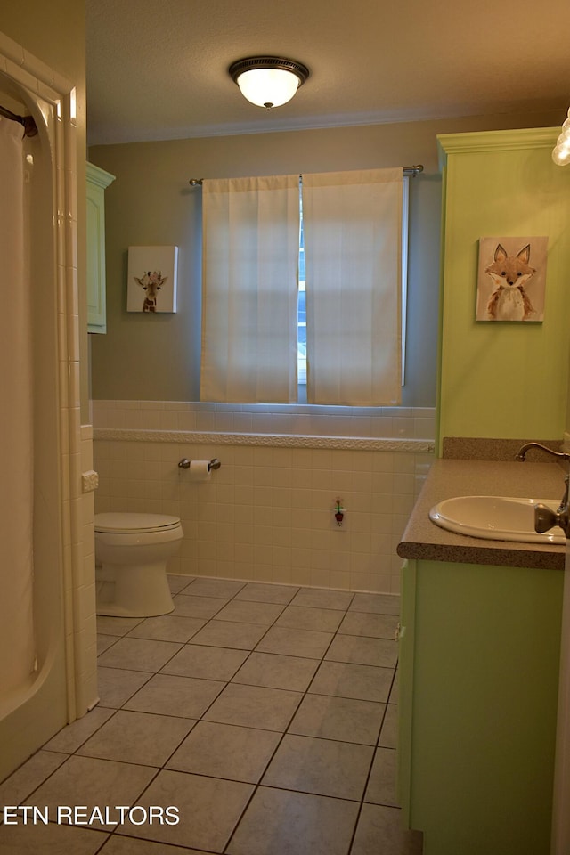 bathroom featuring toilet, tile patterned flooring, tile walls, and vanity