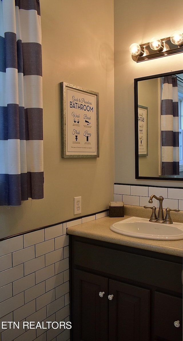 bathroom featuring vanity and tile walls