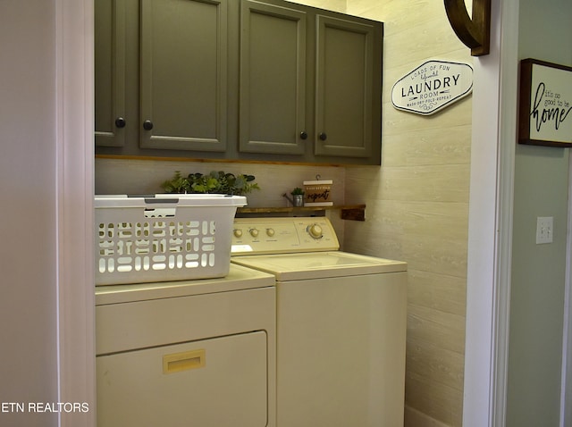 laundry area featuring cabinets, separate washer and dryer, and wooden walls